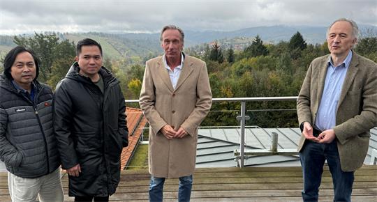 Das Foto zeigt vier Männer auf einer Holz-Terrasse.