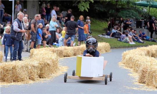 Fast 500 Meter geht es beim Stötterlinger Seifenkistenrennen die abschüssige Dorfstraße hinab – dabei muss auch eine Schikane gemeistert werden. Zuschauer säumen die Rennstrecke.