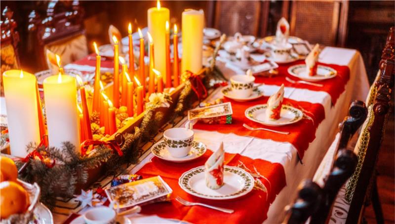 Das Foto zeigt eine festlich gedeckte Tafel mit Kerzenlicht.