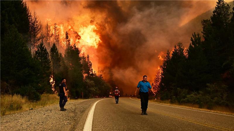 Feuerwehrleute gehen auf einer Straße während eines Waldbrandes in Argentinien.