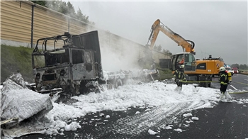 Feuerwehrleute löschen den Lastwagen mit Schaum.