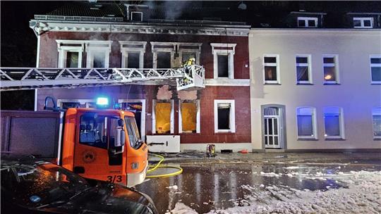 Feuerwehrleute löschen von einer Drehleiter aus ein Mehrfamilienhaus in Essen.