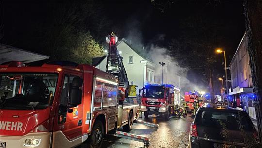 Feuerwehrleute löschen von einer Drehleiter ein Haus.