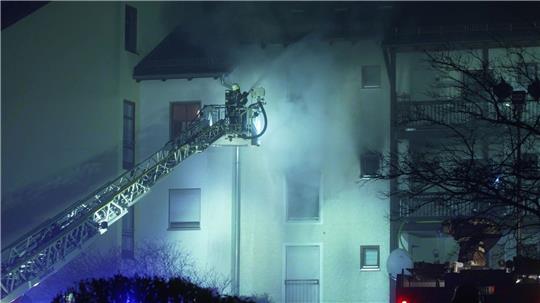 Feuerwehrleute sind bei einem Brand in einem Mehrfamilienwohnhaus in Bayern im Einsatz.