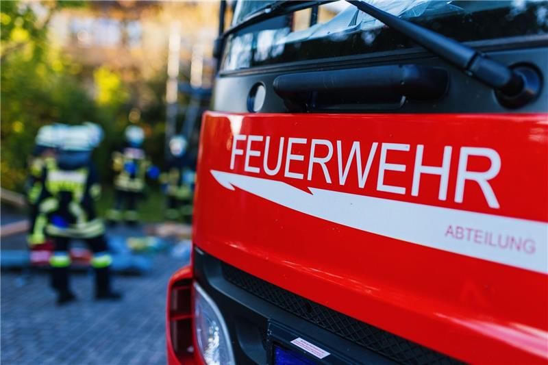 Feuerwehrleute stehen hinter einem Einsatzfahrzeug.