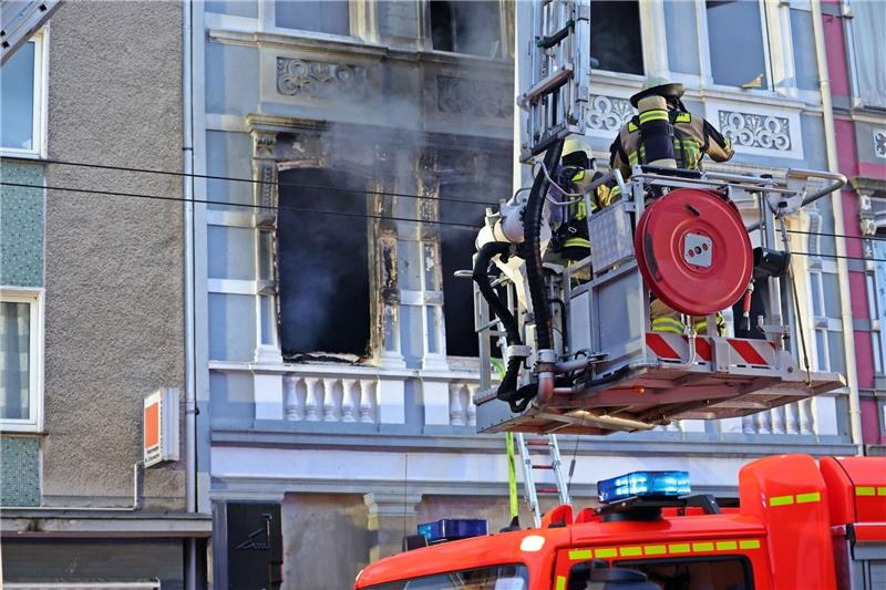 Solingen: Familie mit zwei Kindern stirbt bei Brand Feuerwehrmänner stehen vor dem Mehrfamilienhaus, in dem es gebrannt hat.