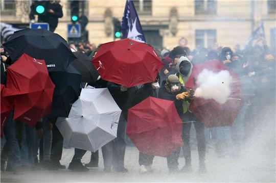 Feuerwerkskörper werden abgeschossen, Menschen verstecken sich hinter Regenschirmen: Proteste in Nantes.