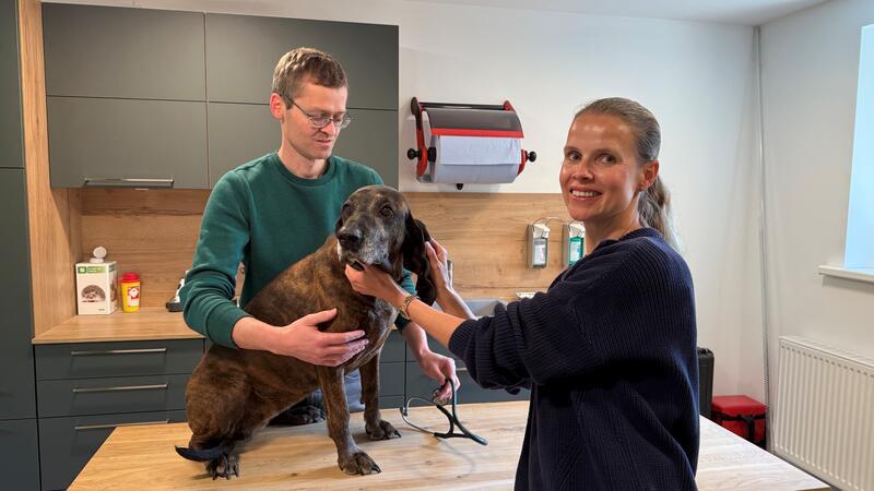 Fichte, der Hund von Vater Hubertus Finsterwalder, ist nicht krank. Er stellt sich nur für das Foto mit Fabian und Nadine Finsterwalder auf den Untersuchungstisch.