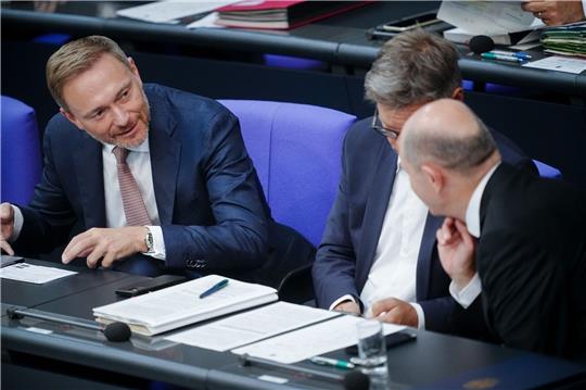 Finanzminister Christian Lindner (l) spricht mit Bundeskanzler Olaf Scholz (r). Dazwischen sitzt Wirtschaftsminister Robert Habeck (Archivbild).