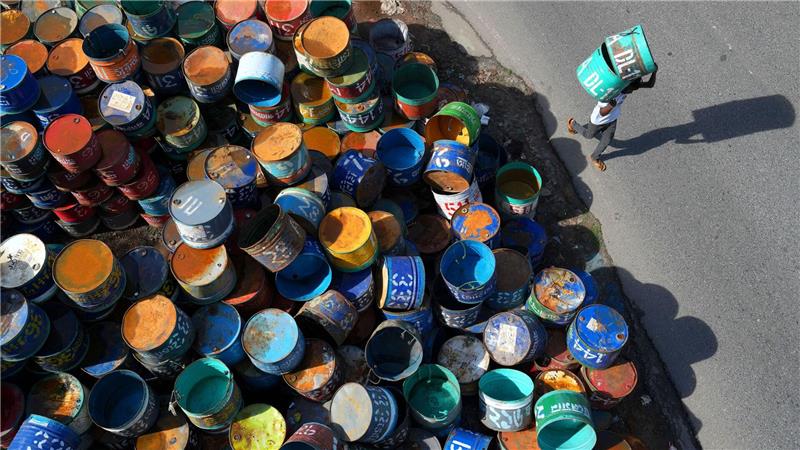 Fisch in bunten Dosen: Arbeiter im Bezirk Rangamati in Bangladesch tragen Metallfässer, die für den Transport von Fisch verwendet werden. 
