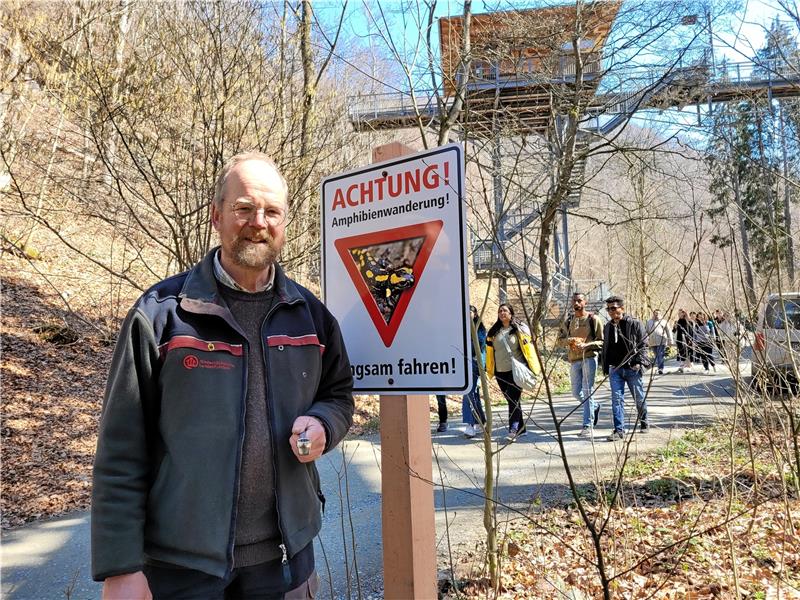Bad Harzburg: Forst sperrt die Waldstraße ins Kalte Tal Förster Jörg Sonnabend neben einem der Warnschilder, die er im Kalten Tal aufgestellt hat. Im Hintergrund ist gut zu sehen, was auf dem Waldweg bei schönem Wetter los sein kann: Zahlreiche Menschen, überwiegend Touristen, bewegen sich im Bereich des Baumwipfelpfads. Foto: Exner