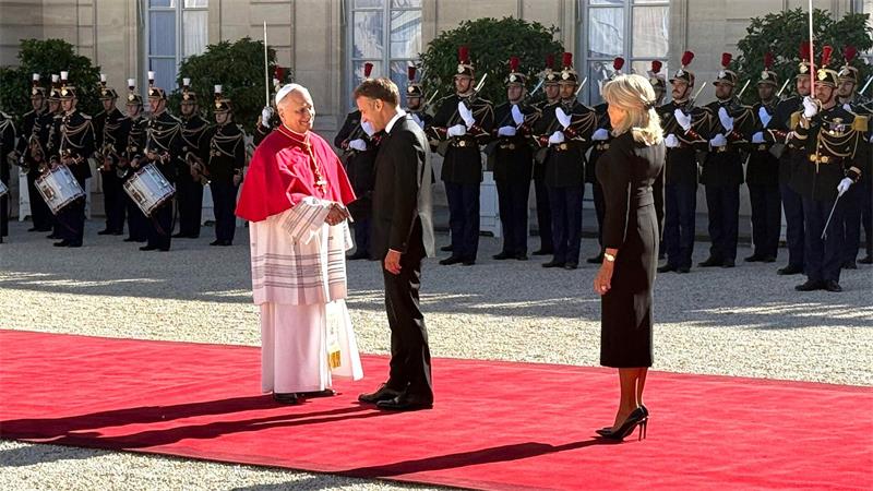 Frankreichs Präsident Emmanuel Macron und seine Ehefrau Brigitte schütteln Hände mit dem Papst im Hof des Élysée-Palastes.