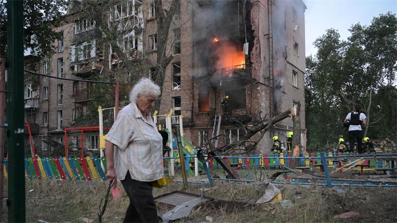 Frau passiert brennendes Wohnhaus nach russischem Angriff in Kiew