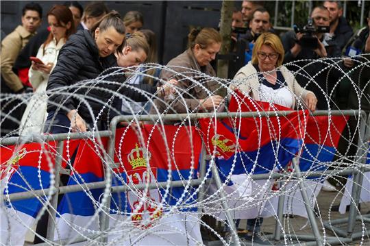 Frauen befestigen serbische Flaggen an einem Zaun vor dem Rathaus während einer Demonstration in der Stadt Zvecan im Norden des Kosovo.