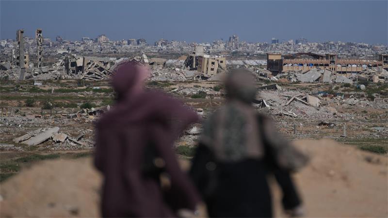 Frauen blicken auf ein stark zerstörtes Gebiet im Zuge des Gaza-Kriegs.