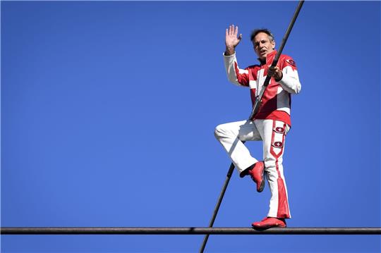 Freddy Nock balanciert auf einem Seil einer Seilbahn.