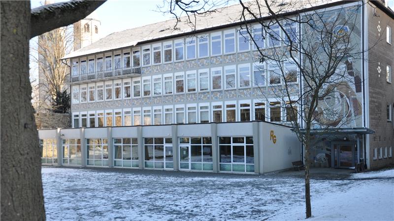 Mehrstöckiges Schulgebäude mit vielen Fenstern und verschneitem Vorplatz