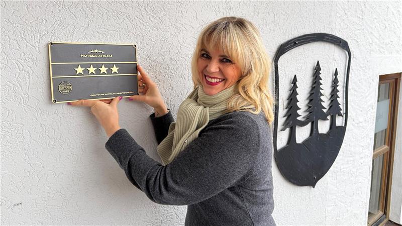 Das Foto zeigt eine blonde Frau, die ein Schild hält, auf dem vier Sterne abgebildet sind.