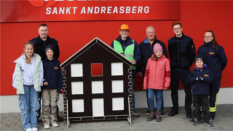 Freude bei der Feuerwehr, stellvertretender Jugendfeuerehrwart Marcel Meininger, Vorsitzender Bergstadtverein Andreas Schröder, Firmeninhaber Tischlerei Koch Frank Koch und die Betreuer der Kinderfeuerwehr Jason Eberhard, Anke Tinius (hintere Reihe von links) und vier Mädchen und Jungen der Kinderfeuerwehr über das neue Häuschen.