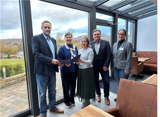 Freudig überreicht Landesbeauftragte Dr. Ulrike Witt (2.v.l.) den Förderbescheid an Marc Kühne (links) und seine Frau Beatrice (Mitte) im neuen Wintergarten des Hotels Brunnenbach. Edda Schaper von der Wirego und Bürgermeister Wolfgang Langer freuen sich ebenfalls über den erfolgreichen Generationswechsel. Foto: Eggers