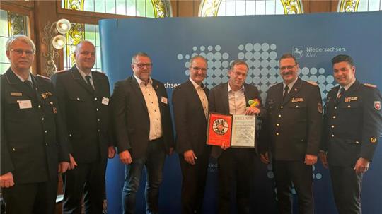 Freuen sich über die Auszeichnung (v.li.): Kreisbrandmeister Uwe Fricke, Gemeindebrandmeister Christoph Schubert, Bürgermeister Alf Hesse, Staatssekretär Stephan Manke, Hans-Christian Fontheim, Olaf Kapke (Präsident Landesfeuerwehrverband) und Regierungsbrandmeister Tobias Thurau.
