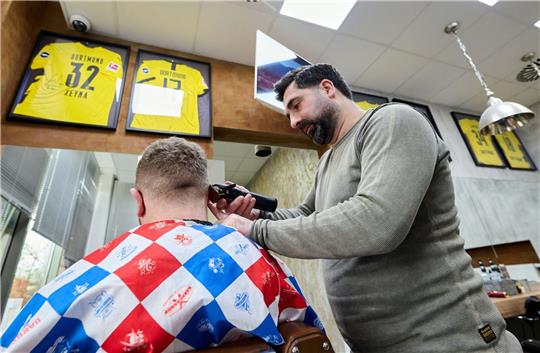 Friseur Taner Dogan schneidet in seinem Salon in einer Netto-Filiale einem Kunden  die Haare.