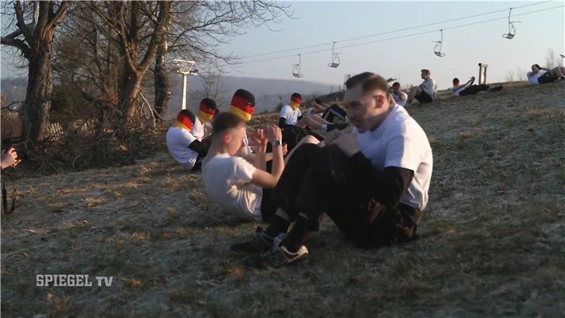 Das Foto zeigt Jugendliche und junge Erwachsene, die teilweise mit schwarz-rot-goldenen Sturmhauben Frühsport machen.