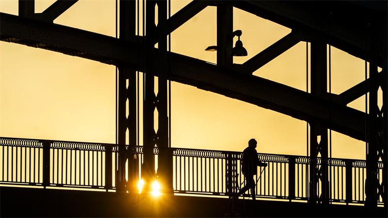 Frühsport im Sonnenaufgang - Nordic Walker auf der Osthafenbrücke in Frankfurt.