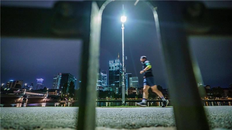 Frühsport in der Banken-Stadt: Ein Jogger läuft am frühen Morgen vor der Skyline von Frankfurt am Main.