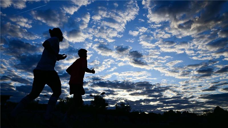 Bilder des Tages Frühsport in der Hauptstadt: Zwei Jogger laufen am Morgen in Berlin unter einem bewölkten Himmel.