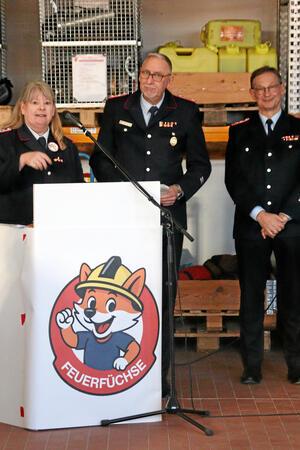 Drei Personen stehen an einem Rednerpult.