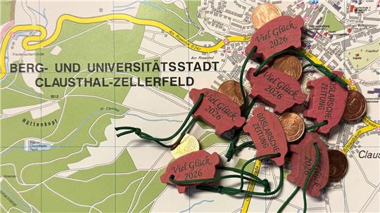 Eine Handvoll Glücksschweinchen liegt auf der Straßenkarte von Clausthal-Zellerfeld.