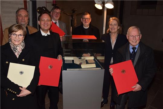 Für Elke Brummer, Vorsitzende des Fördervereins der Marktkirchenbibliothek, Helmut Liersch, Dr. Patrik Schnabel, Propst Thomas Gunkel, Landesbischof Dr. Christoph Meyns und Professor Johannes Lähnemann (v.l.) hat Marianne Kothé (2.v.r.) Sonderalben mit der Gedenkbriefmarke parat. Im Schaukasten ist das berühmte Gesangbuch zu bewundern. Fotos: Kleine