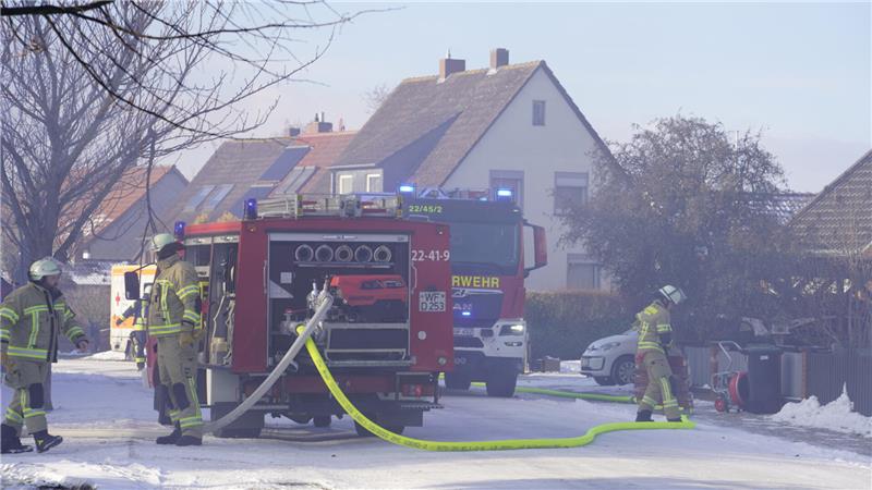 Feuerwehrmänner stehen an einem Feuwehrauto mit Wasserschlauch