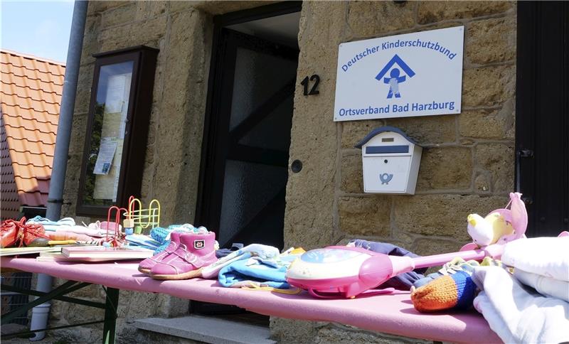 Kleidertauschzentrale gewinnt an Bedeutung Für den zusätzlichen Öffnungstag während der Sommerferien wird vor den Räumen des Kinderschutzbundes mit einem Tisch voll Spielzeug und Kleidung. geworben.