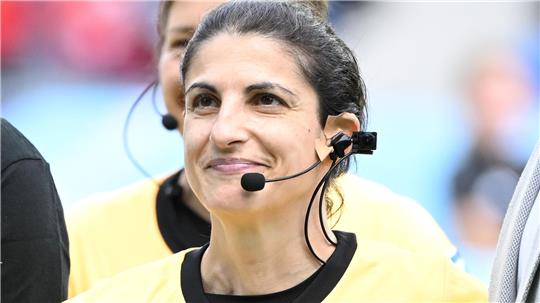 Schiedsrichterin in gelbem Trikot und mit Headset.
