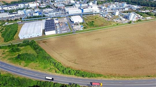 Luftaufnahme eines Industriegebiets mit mehreren großen Gebäuden neben einem Feld und einer Straße