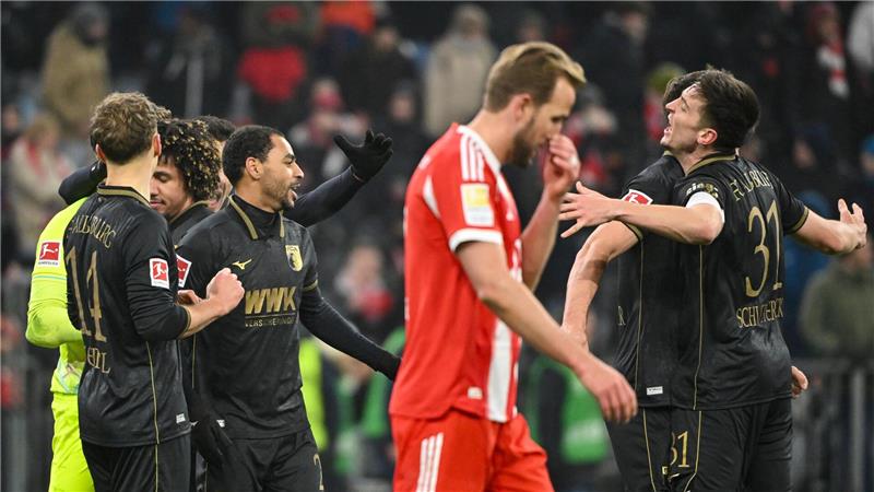 Fußball: Bundesliga, FC Bayern München - FC Augsburg, 19. Spieltag, Allianz Arena. Die Spieler des FC Augsburg jubeln nach Spielende. Davor geht Harry Kane (Bayern München). Das Spiel endete 1:2.