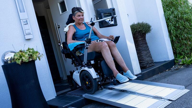 Gabriele Engel fährt mit ihrem Rollstuhl über eine Rampe aus ihrem Haus.