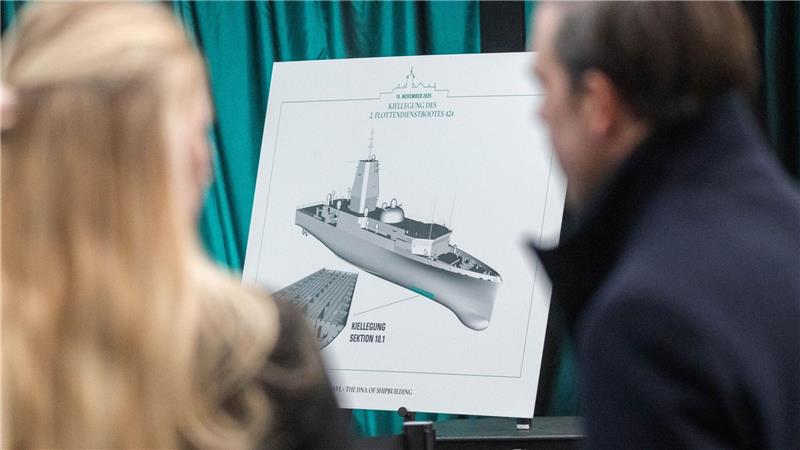 Gäste betrachten in der Werfthalle der Peene-Werft eine Zeichnung des neuen Flottendienstbootes. 