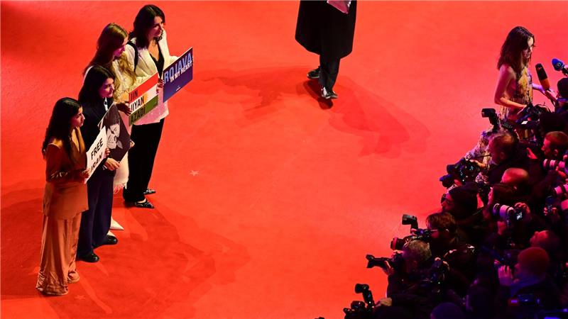 Gäste, darunter die deutsch-iranische Schauspielerin Jasmin Tabatabai (2. v. l.), halten Protestschilder hoch.