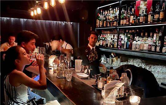 Gäste sitzen am Tresen einer Bar in Bangkok.