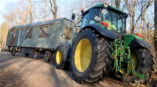 Ein Trecker zieht einen alten Bauwagen.