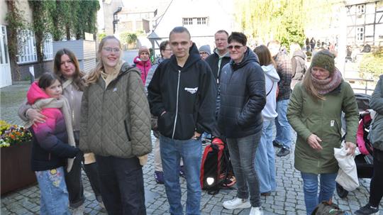 Gruppe von Menschen in Winterkleidung auf gepflastertem Platz vor Fachwerkhäusern