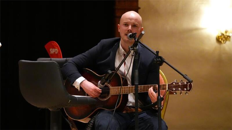 Gastgeber Christoph Willeke stimmt auf der Gitarre mit seinen Gästen das Lied „Die Gedanken sind frei“ an.