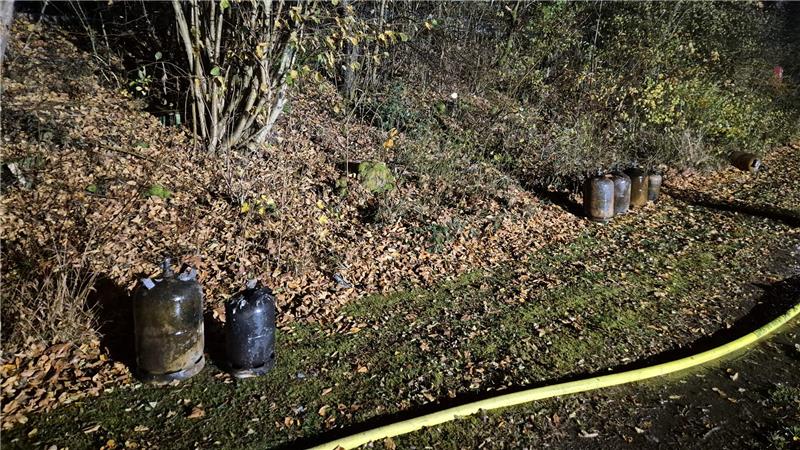 Nach Brand auf Campingplatz: Luftaufnahme zeigt Ausmaß der Zerstörung Mehrere Gasflaschen stehen am Rand eines Weges. Sie zeigen erhebliche Brandspuren.