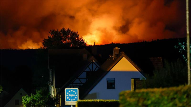 Gefährlich nah: Die Flammen des Brandes im Hohen Venn sind schon hinter einem Haus in Monschau zu sehen. 