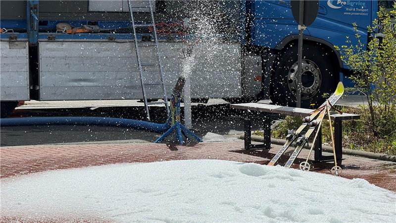 Das Foto zeigt eine Schnee-Maschine, die bei Sonnenschein Schneekörner nach draußen pustet.