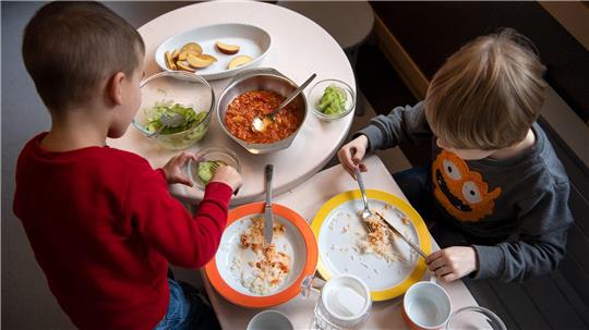 Zwei Kindergartenkinder essen an einem Tisch.