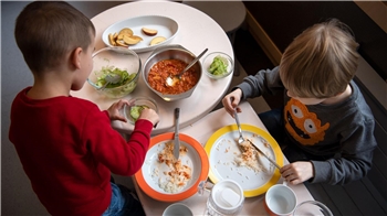 Zwei Kindergartenkinder essen an einem Tisch.